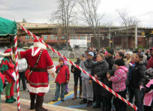 Santa in front of a crowd with is elves